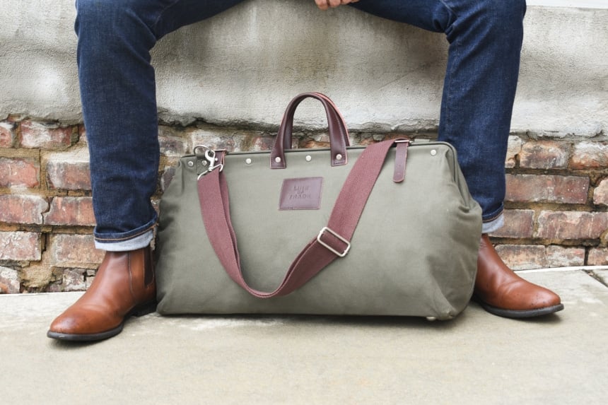 Bespoke Post Weekender Bag Outside Sitting At Feet of Model Wearing Jeans and Boots Close Up