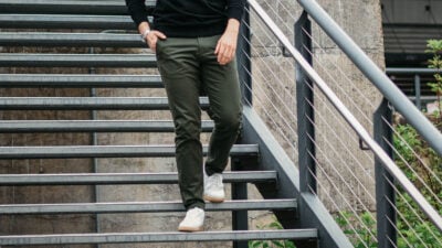2020/02/Best-Chinos-for-Men_-Model-Wearing-Olive-Asket-Chinos-Walking-Down-Stairs-in-White-Sneakers.jpg