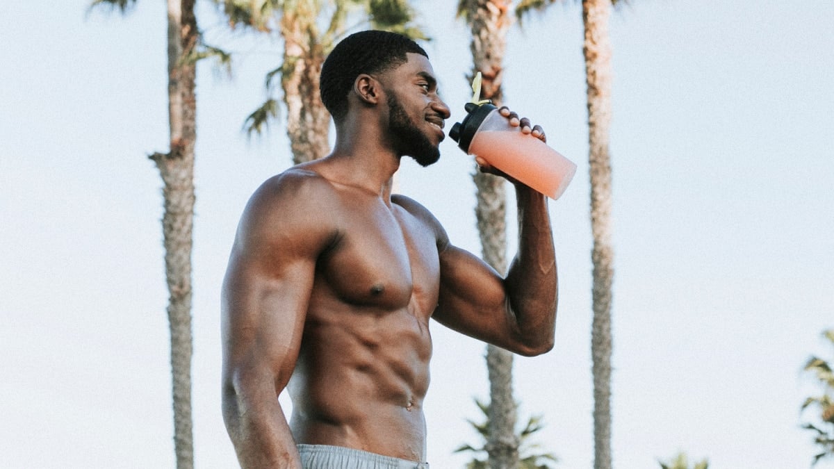 Best Protein Shake Recipes for Muscle Gain Muscular Black Man Smiling and Drinking Protein Shake Outside