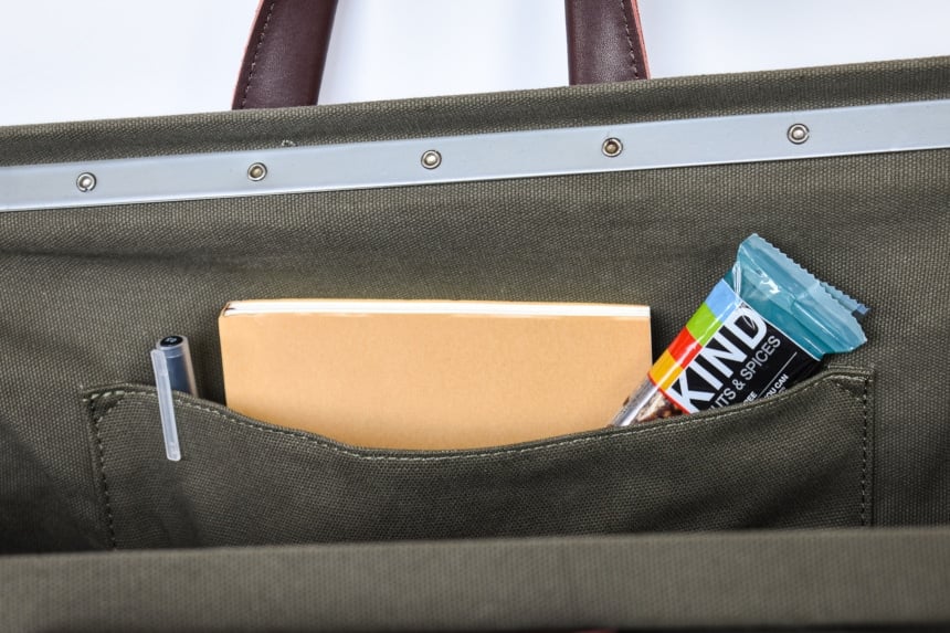 Close up of Inside of Bespoke Post Weekender Bag in Olive Including Protein Bar and Book and Pen in Pocket