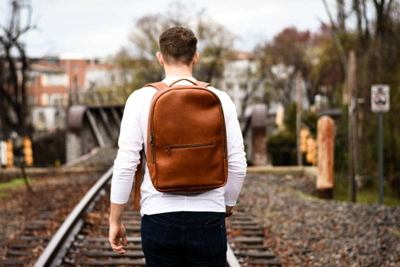 closeup model walking train tracks leather backpack tan