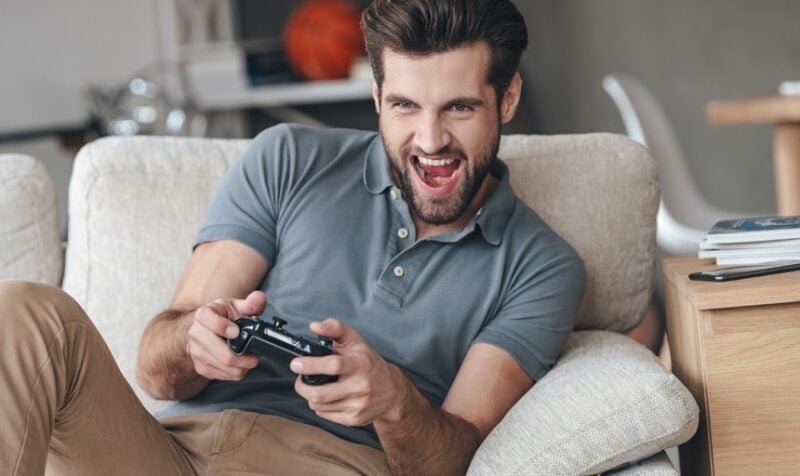 Handsome guy excited to be playing video games on the couch