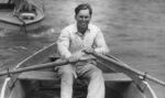 Guy rowing in a rowboat with a jumper on (black and white)