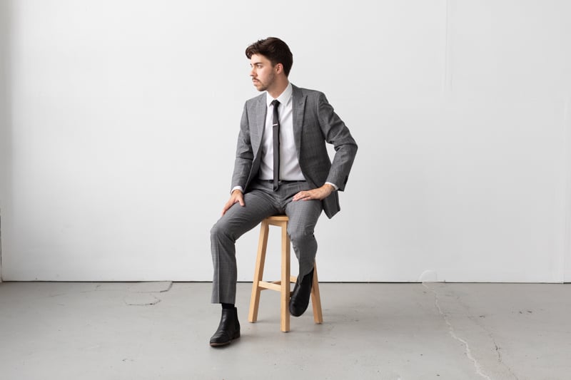 Indochino Harrogate Glen Check Suit model sitting on stool