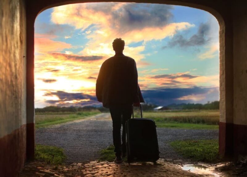Minimalist Travel Items: man holding a suitcase