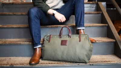 2021/05/Mens-Accessories_-Stylish-Model-Sitting-on-Steps-with-Weekender-Bag-and-Watch-Showing.jpg