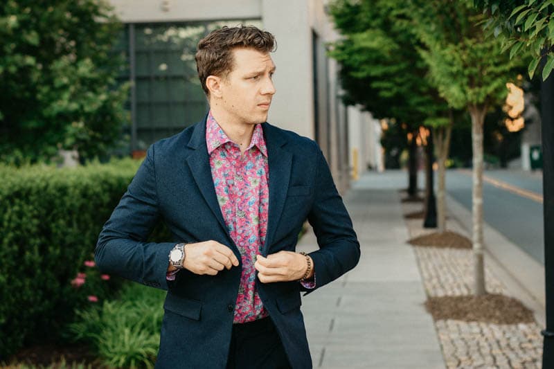 model buttoning up blue suit with pink floral dress shirt underneath