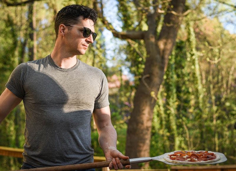 model holding pizza while wearing university heights sunglasses