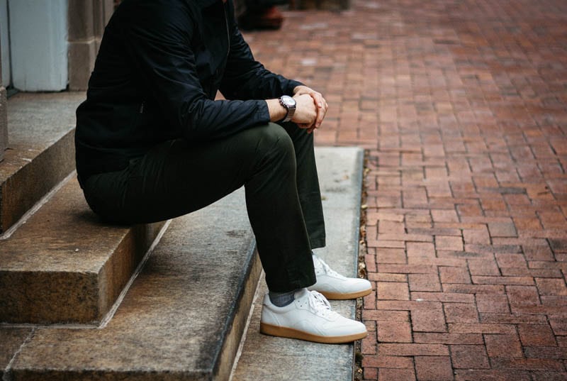 model sitting on concrete step with asket chino everlane tread white sneaker and vincero apex watch