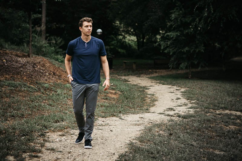 model walking along dirt path wearing rhone notch tee