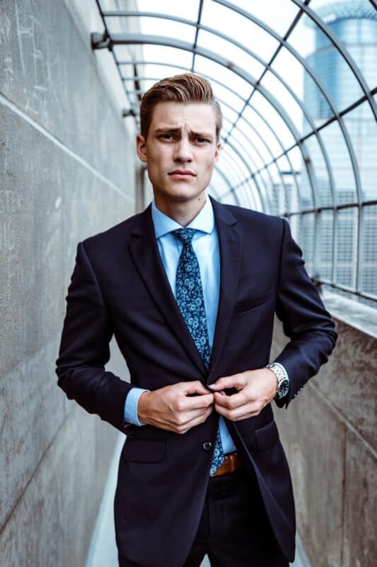 model wearing navy suit and light blue shirt with floral tie