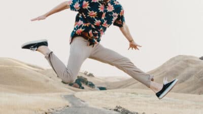 2021/03/Twill-Pants_-Man-Jumping-in-Mid-Air-in-The-Desert-Wearing-Twill-Pantsinos-and-Floral-Shirt-With-Hands-Out.jpg