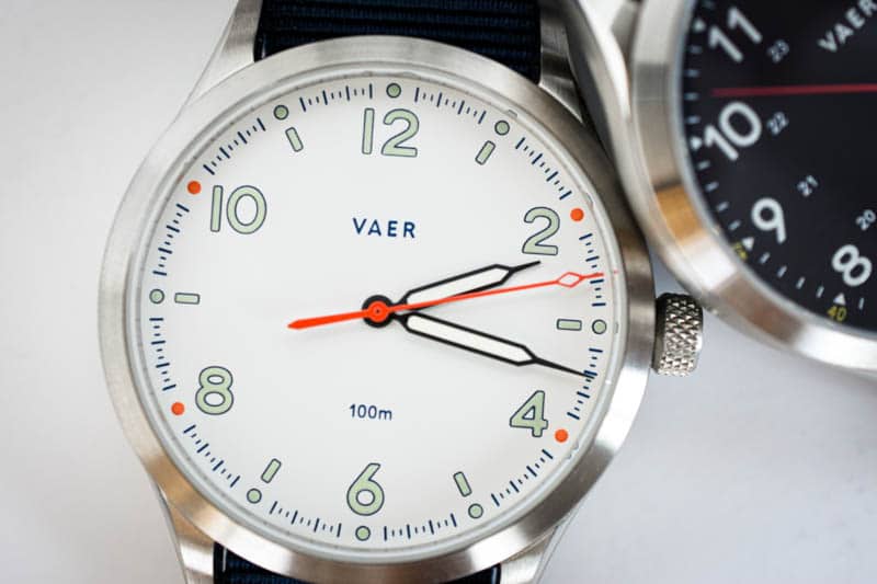 vaer s5 field watch leaned next to c5 black field watch with white background